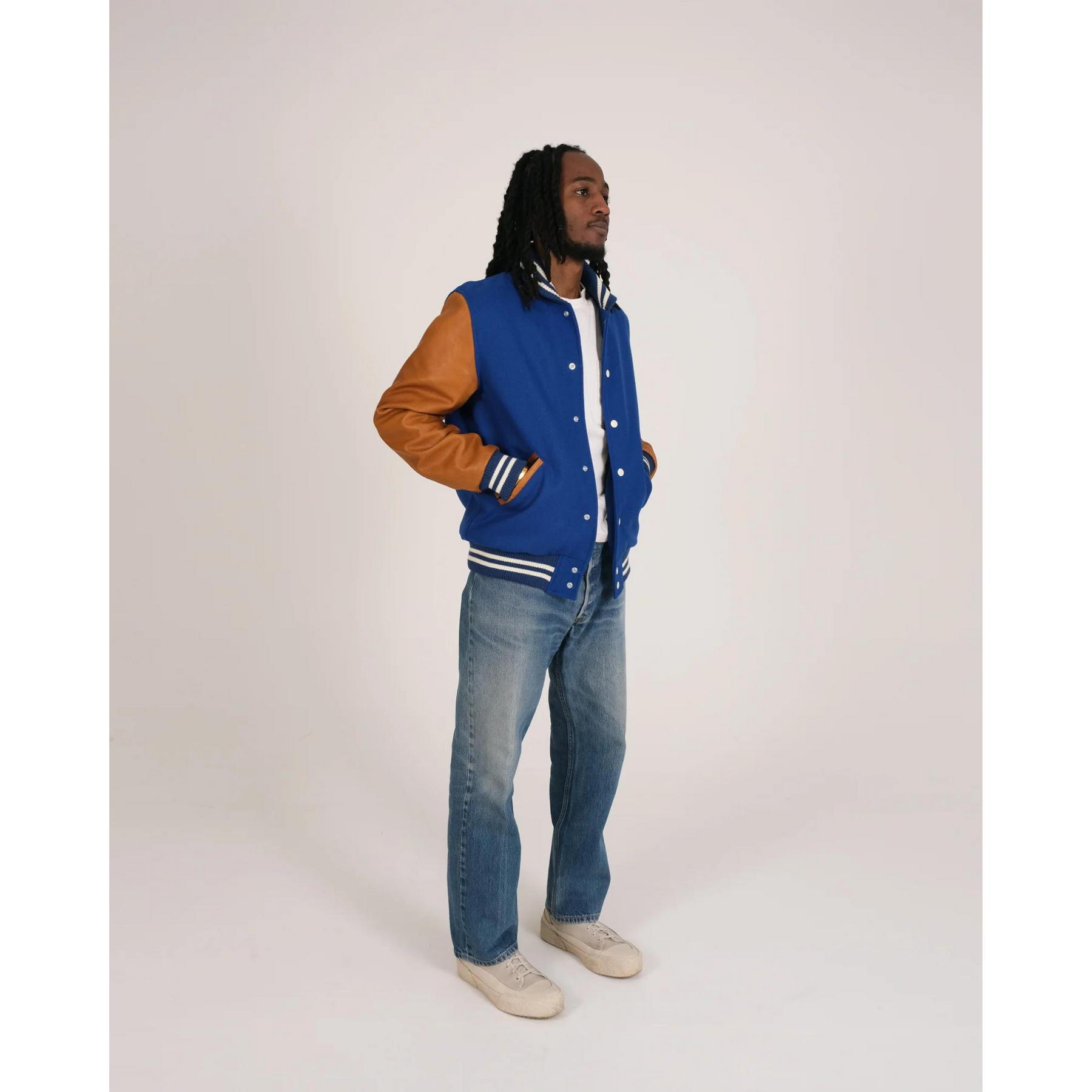 Model wearing blue varsity jacket at an angle