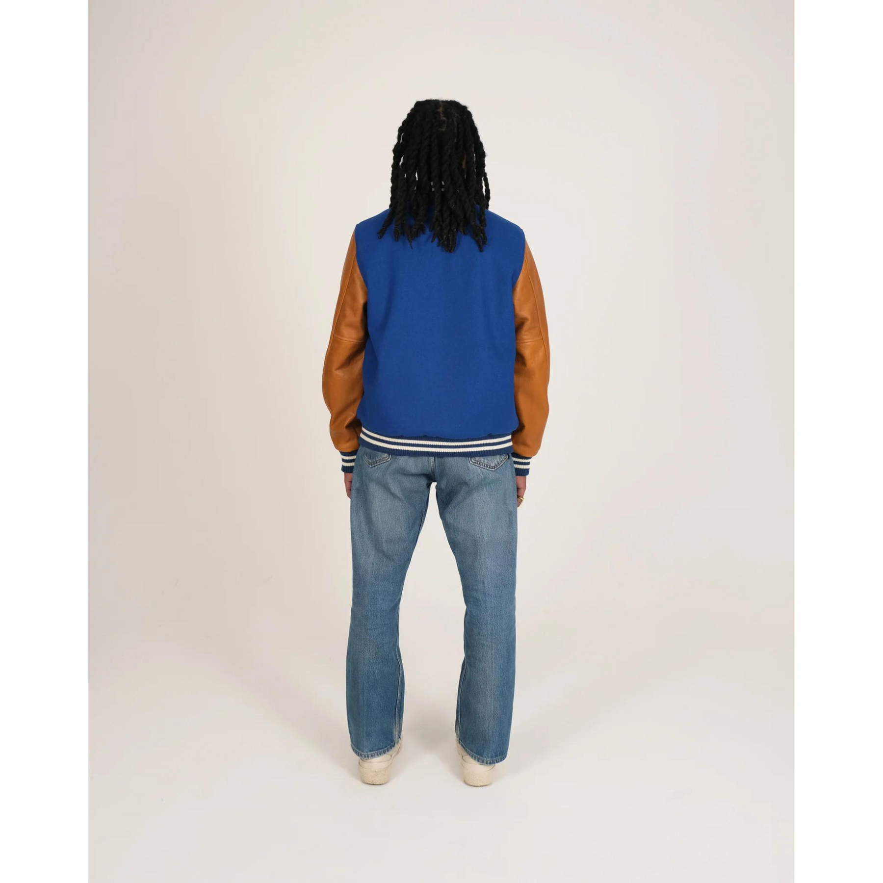 Model wearing blue varsity jacket back view