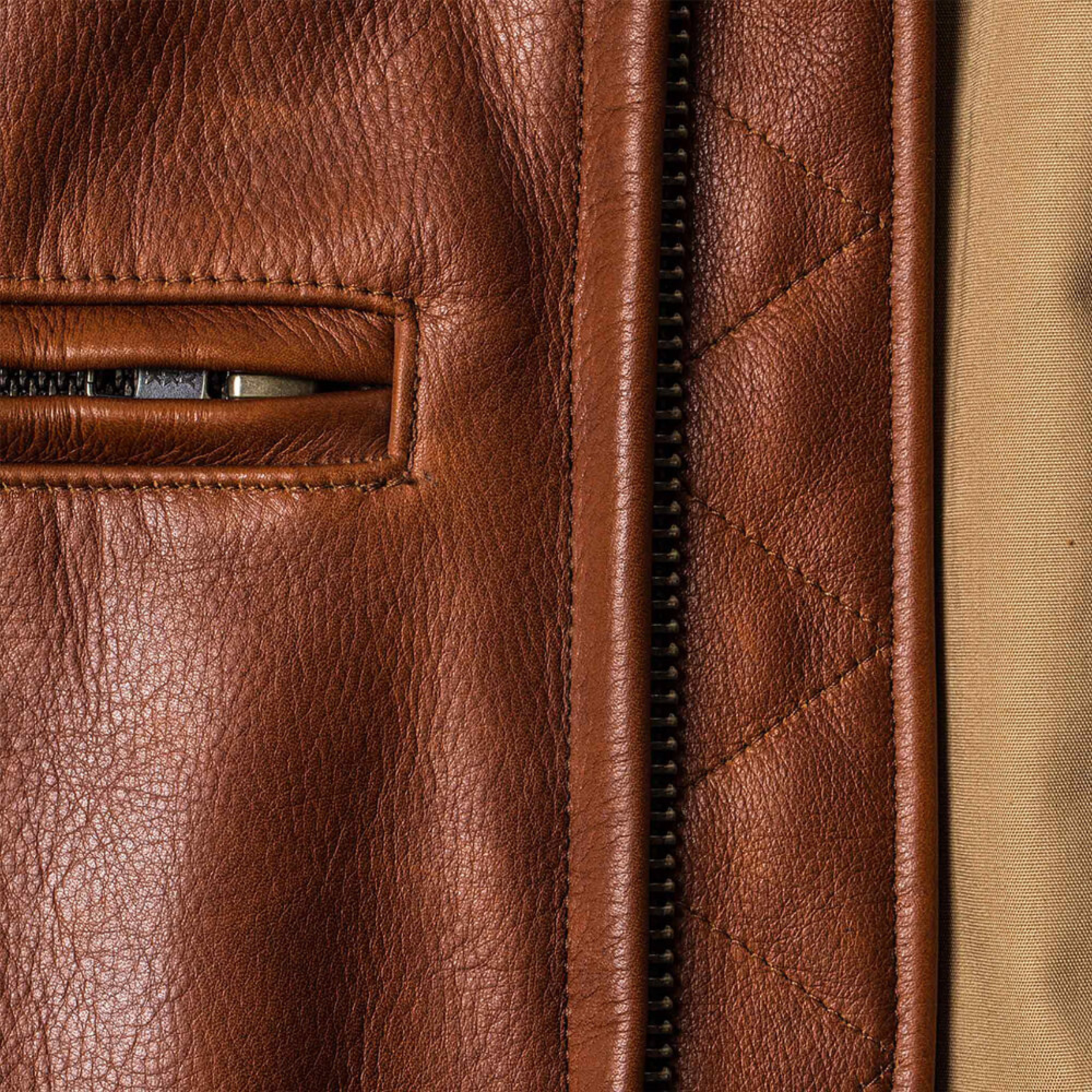 Brown leather jacket with zippered pocket detail.