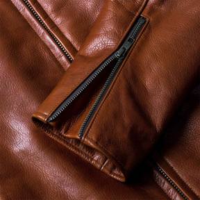 Cuff zipper detail on brown leather rider jacket.