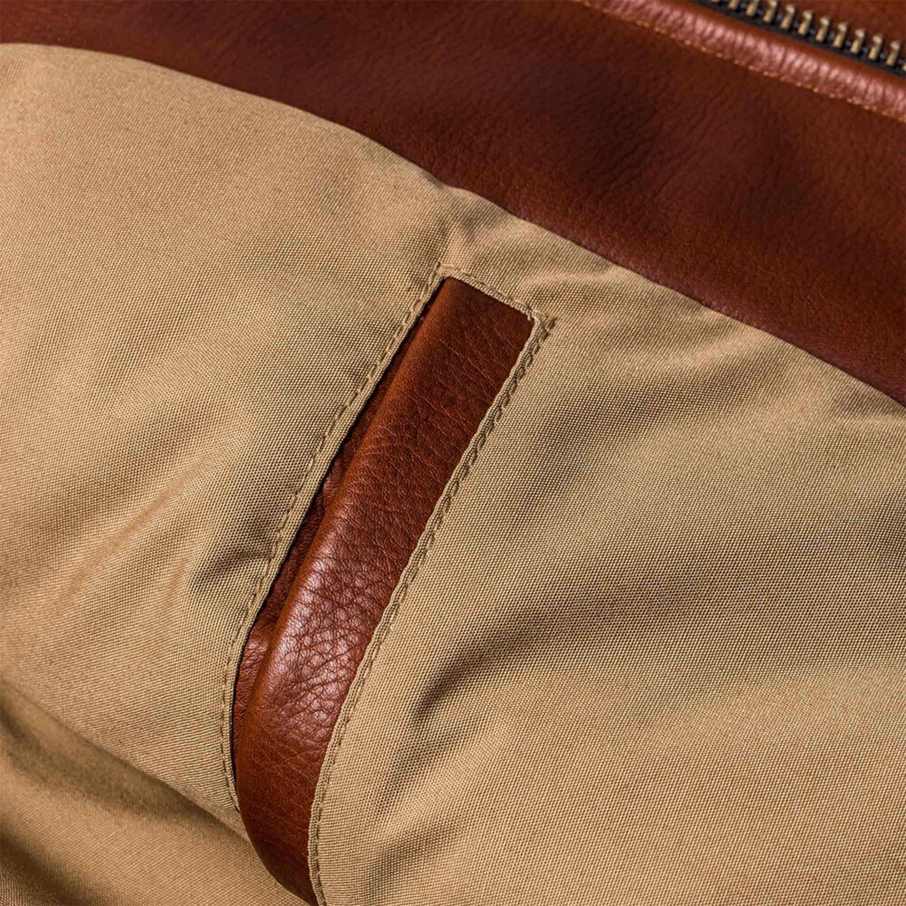 Close-up of pocket detail on brown leather rider jacket.