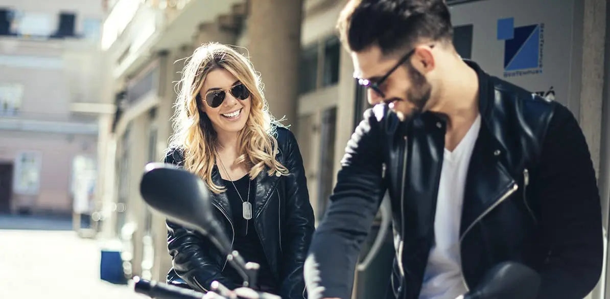 Man and woman wearing black leather jackets in casual street style setting, smiling and enjoying outdoors