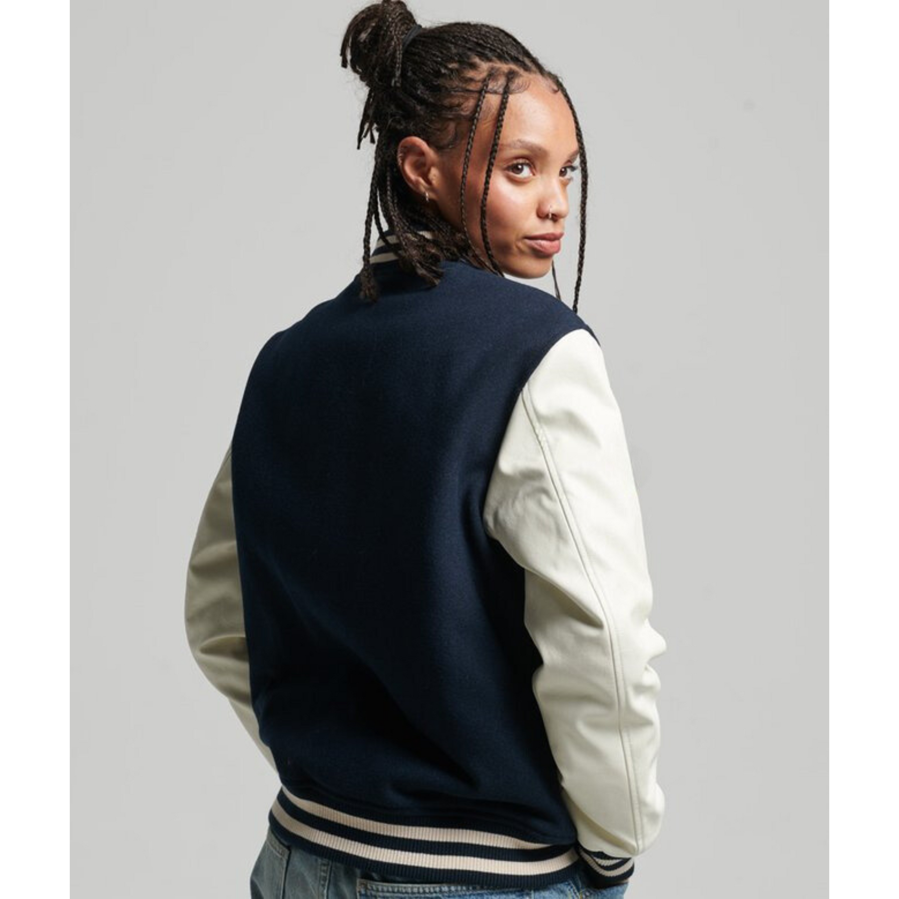 Back view of model wearing navy varsity jacket with white sleeves